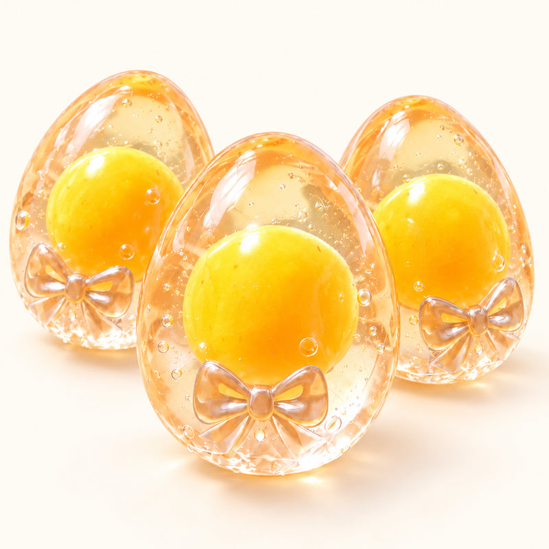 Three SQUEEZU Bow Egg Squishy toys with yellow yolks, clear egg-shaped shells and bow details.