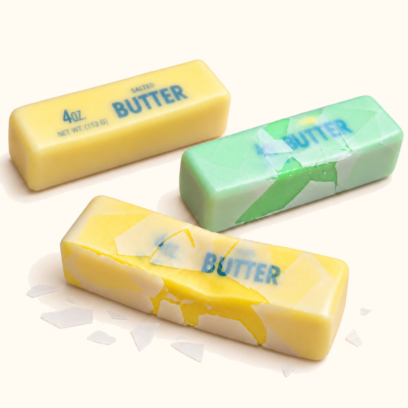 Three yellow and green SQUEEZU Crispy Butter Stick Squishy toys, including a cracked coating example.
