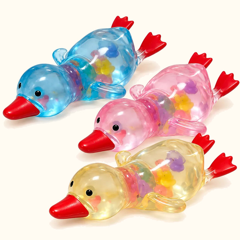 SQUEEZU Duck Squishy toys in translucent blue, pink and yellow with red bills and feet.
