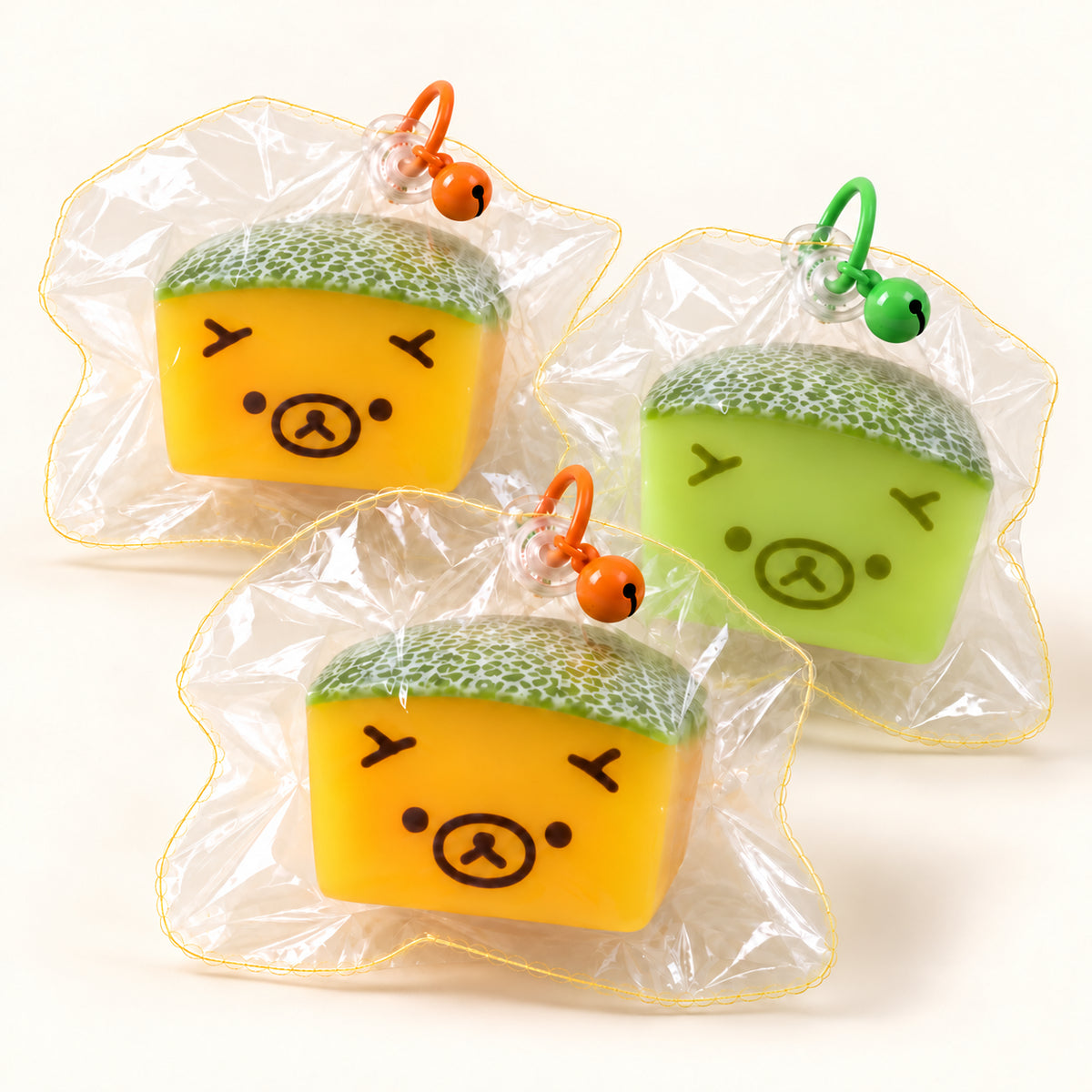 Yellow and green SQUEEZU Melon Bear Squishy toys inside clear pouches with rings and bells.