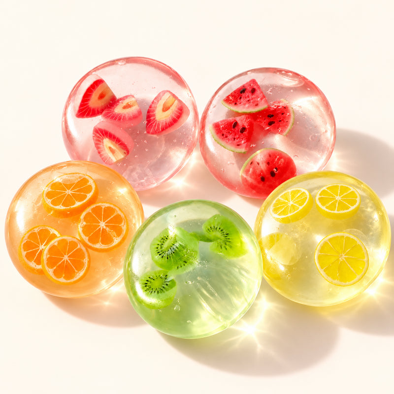 SQUEEZU fruit slice squishy balls with strawberry, watermelon, orange, kiwi and lemon decorations.