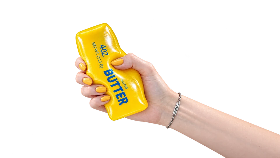 A hand squeezing a yellow butter SQUEEZU