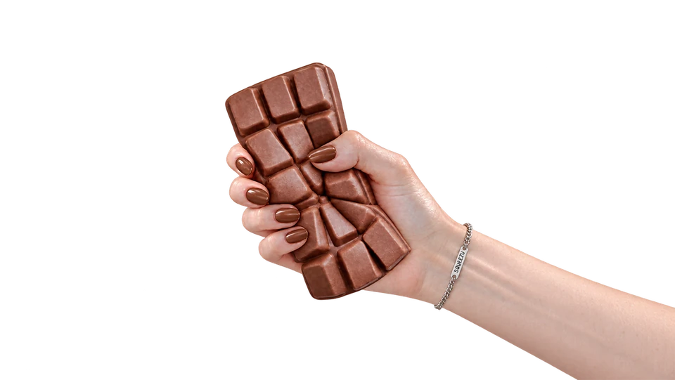 A hand squeezing a chocolate bar SQUEEZU